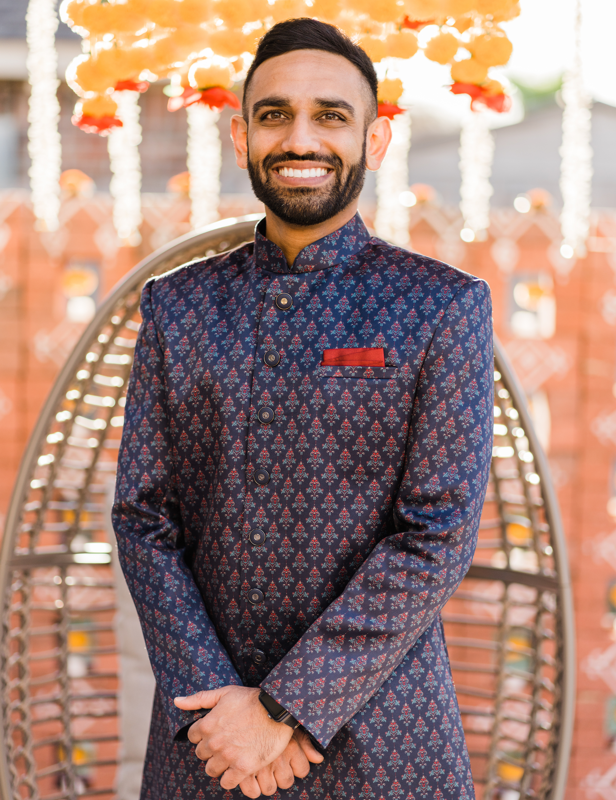 The groom smiles while wearing his traditional Indian wedding attire for a Hindu ceremony. 