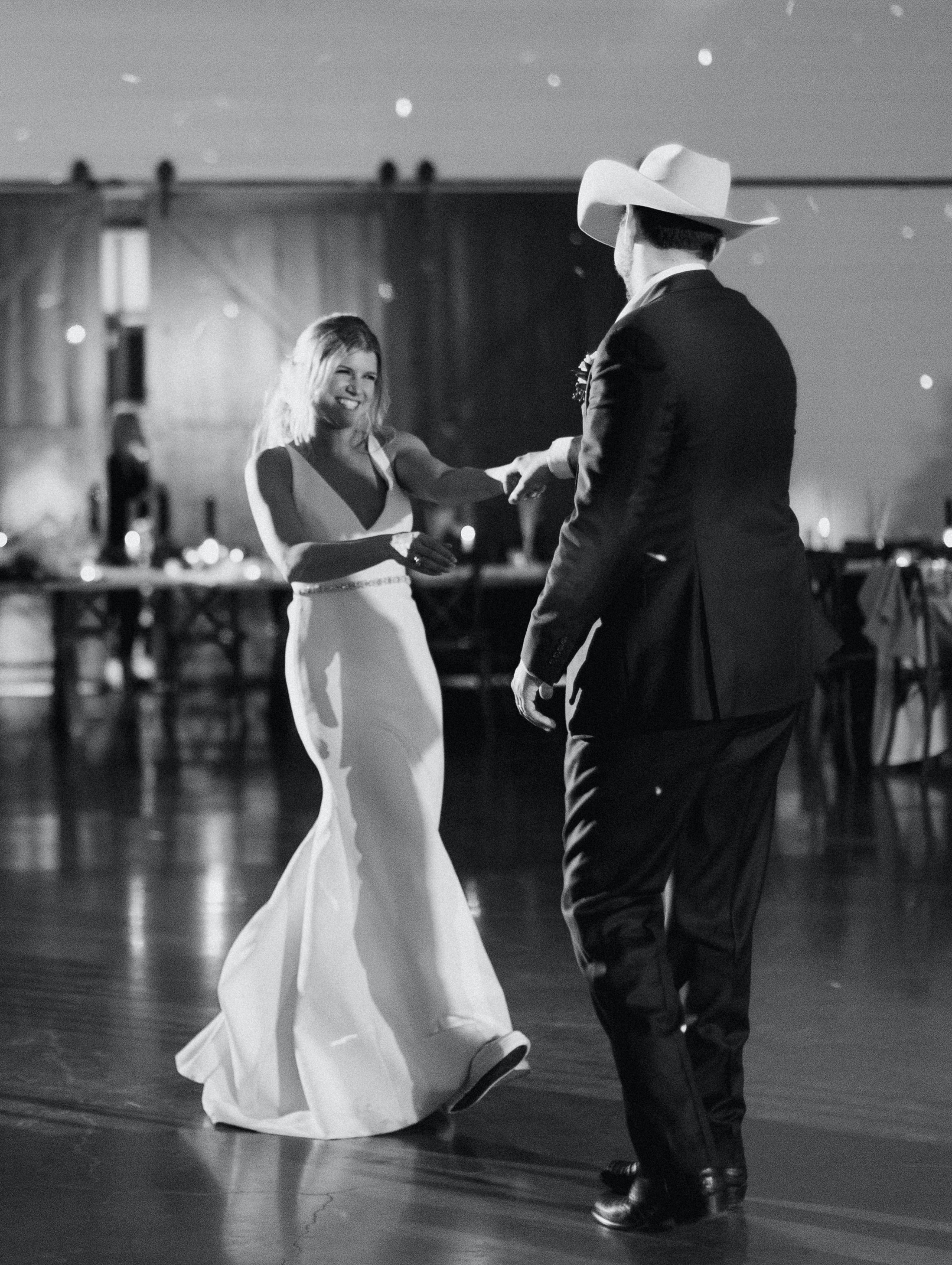 A black and white photo of a bride and groom having their last dance before leaving their wedding venue in Brenham, TX.
