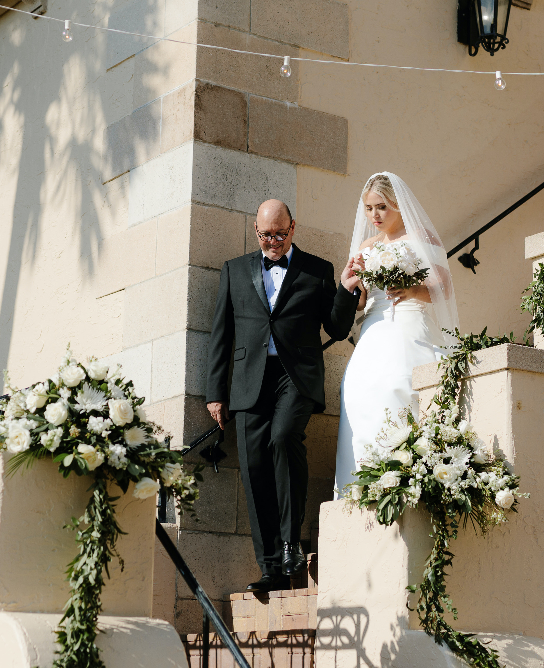 Father of the bride walks a bride down a flight of stairs at the Powel Crosley Estate in Sarasota Florida. 