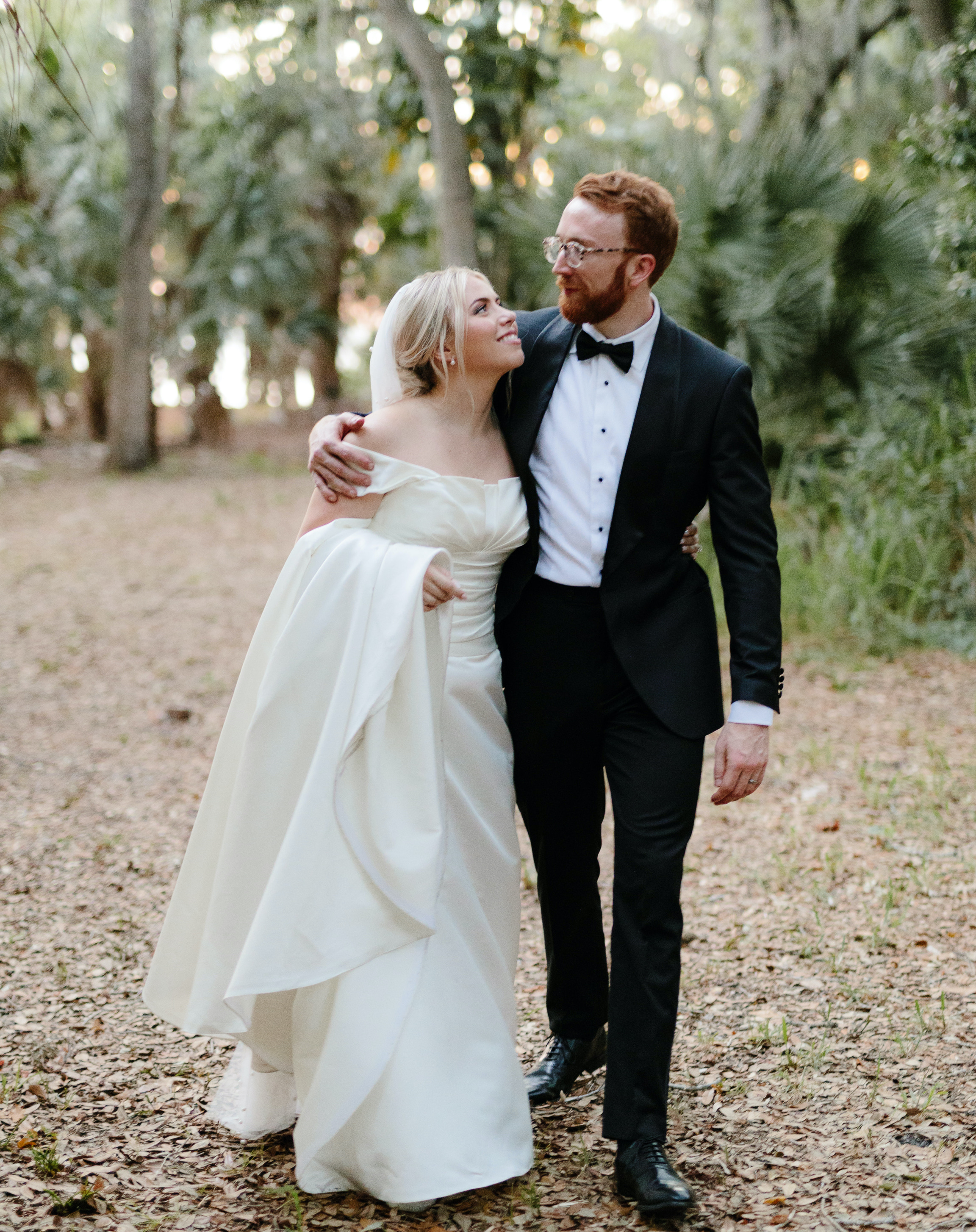 A bride and groom walk together in the woods after their intimate alfresco summer wedding in Sarasota, FL.