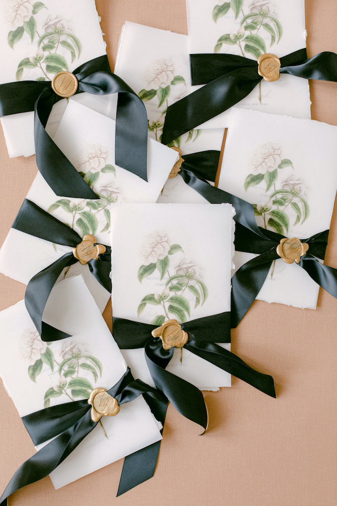 Hand painted custom wedding stationery tied with a silk black ribbon sealed with a gold wax seal by Crane & Palette. 
