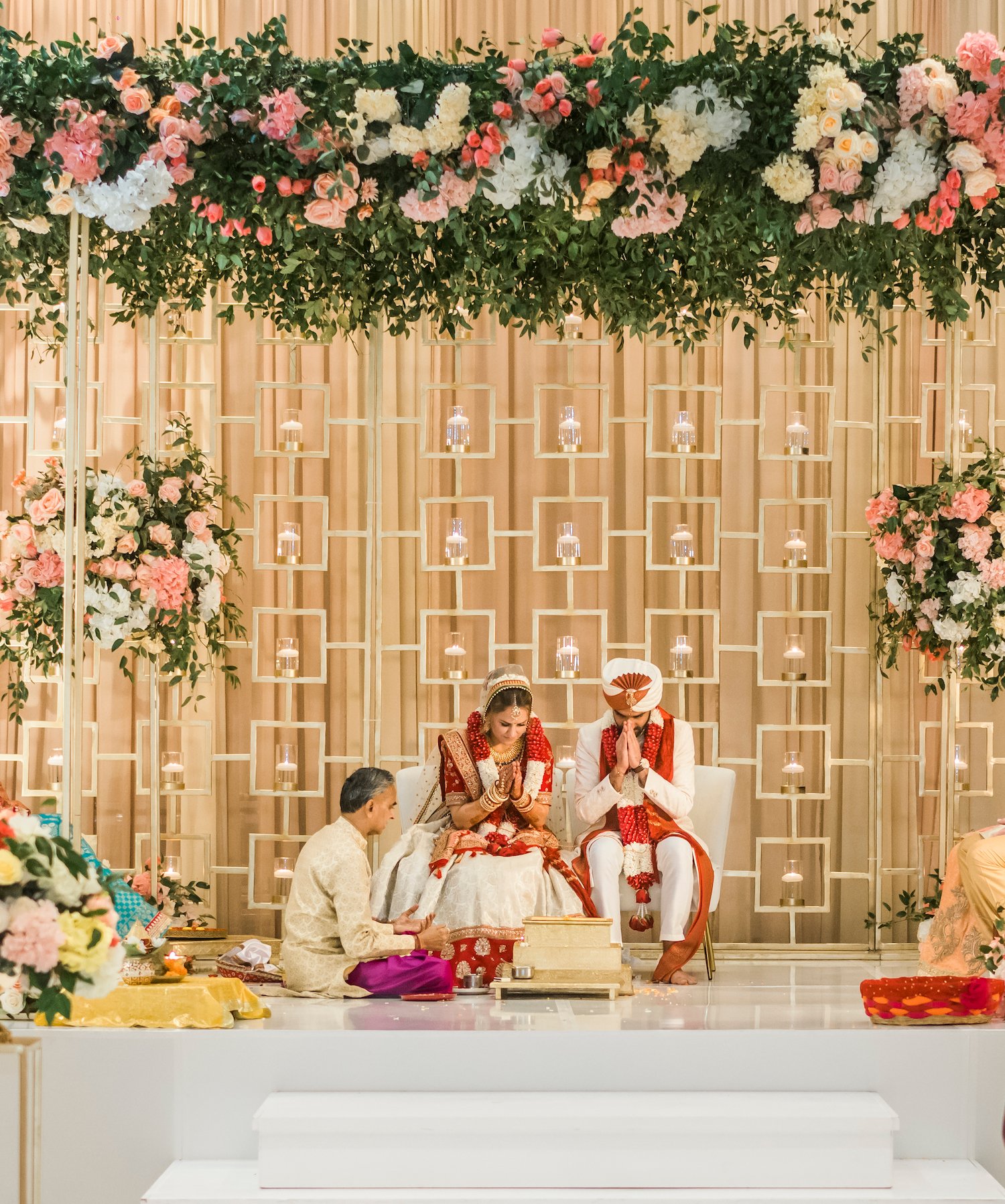 Bride and groom underneath a floral mandap at their Indian American fusion wedding ceremony at Marriott Cityplace at Springwoods Village.