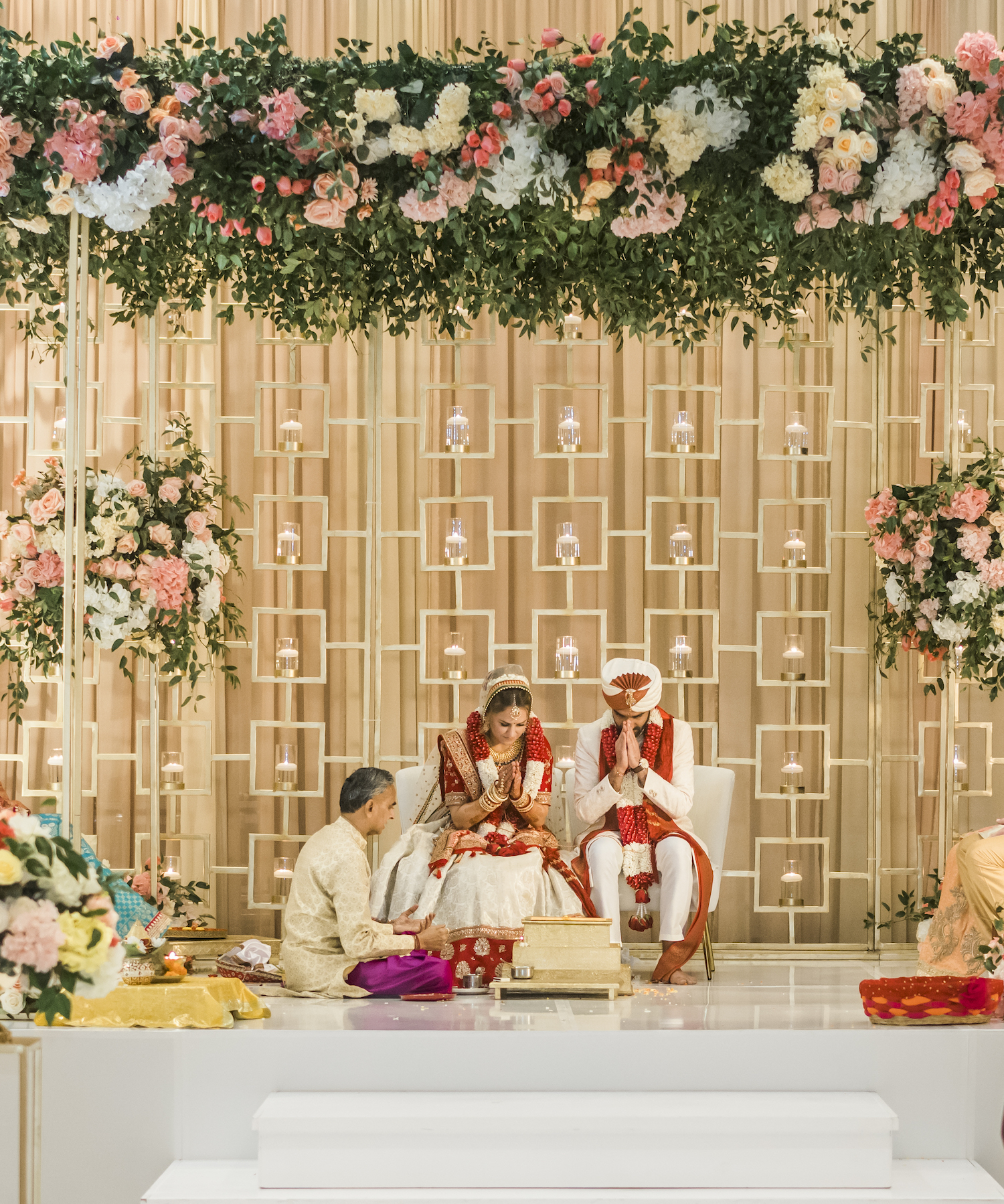 Bride and groom underneath a floral mandap at their Indian American fusion wedding ceremony at Marriott Cityplace at Springwoods Village.