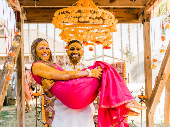 Groom holds the bride in his arms after their Hindu celebration.