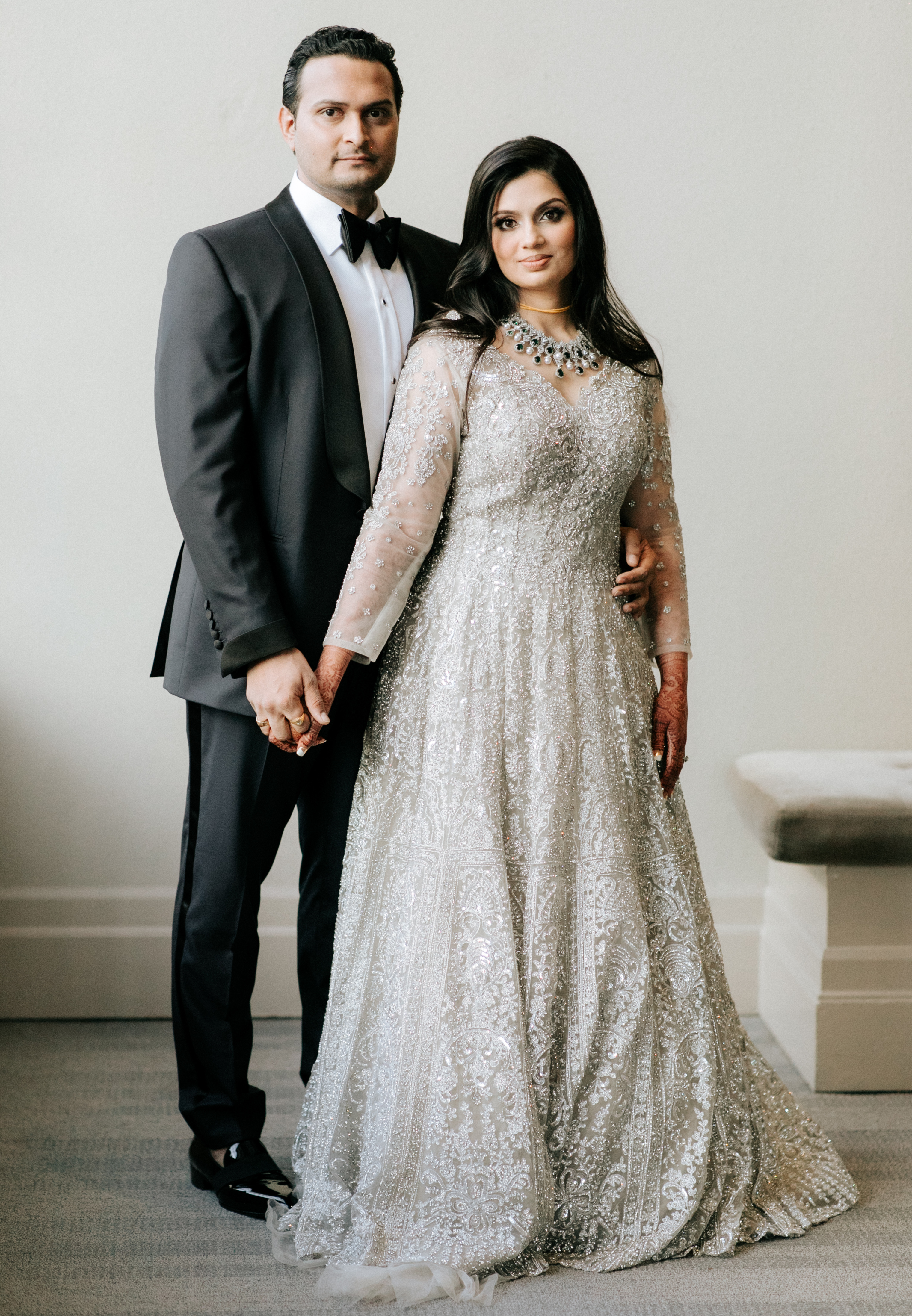 The bride and groom hold hands and pose for the camera. 