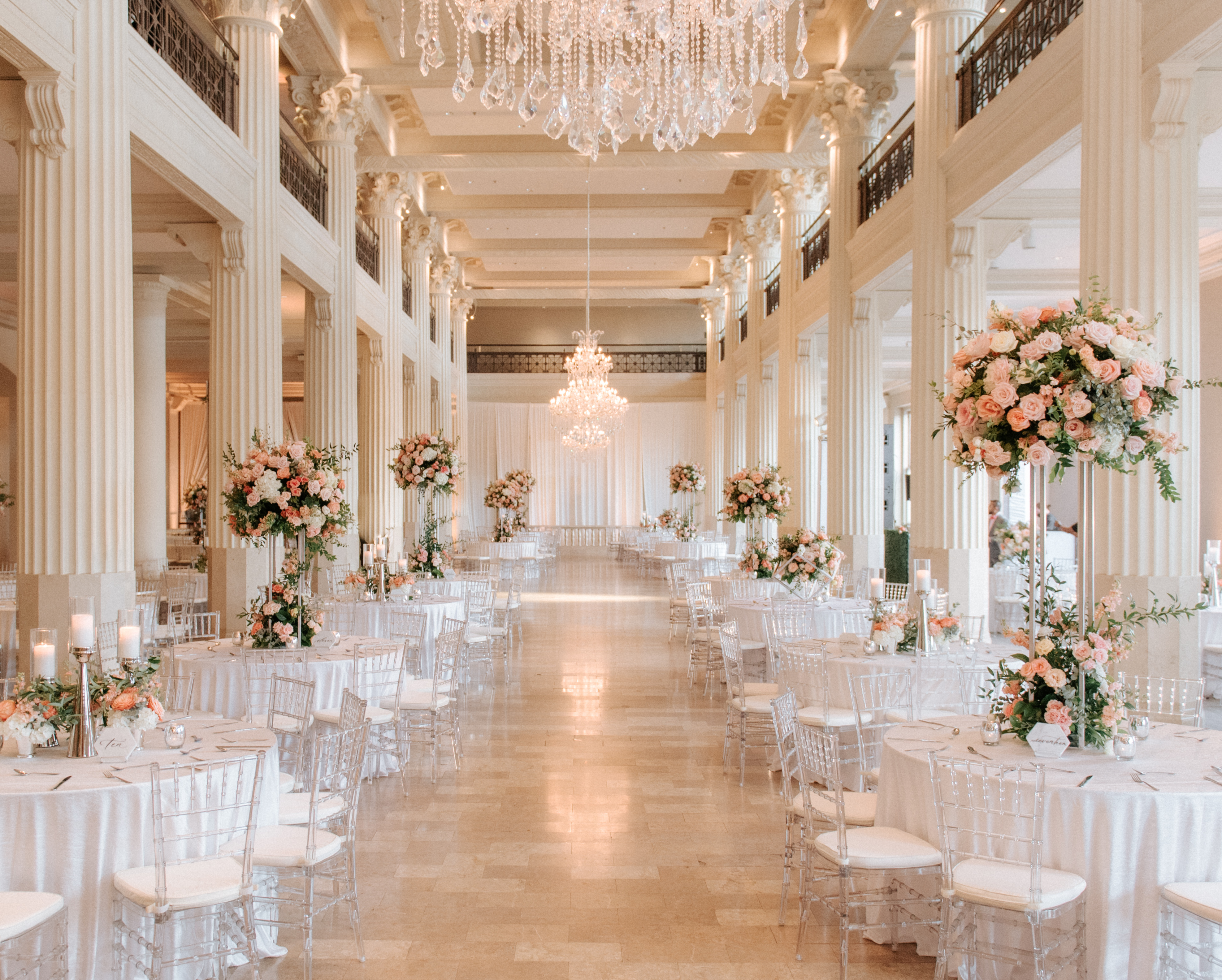 The reception tables are decorated with white, peach and pink floral centerpieces. 