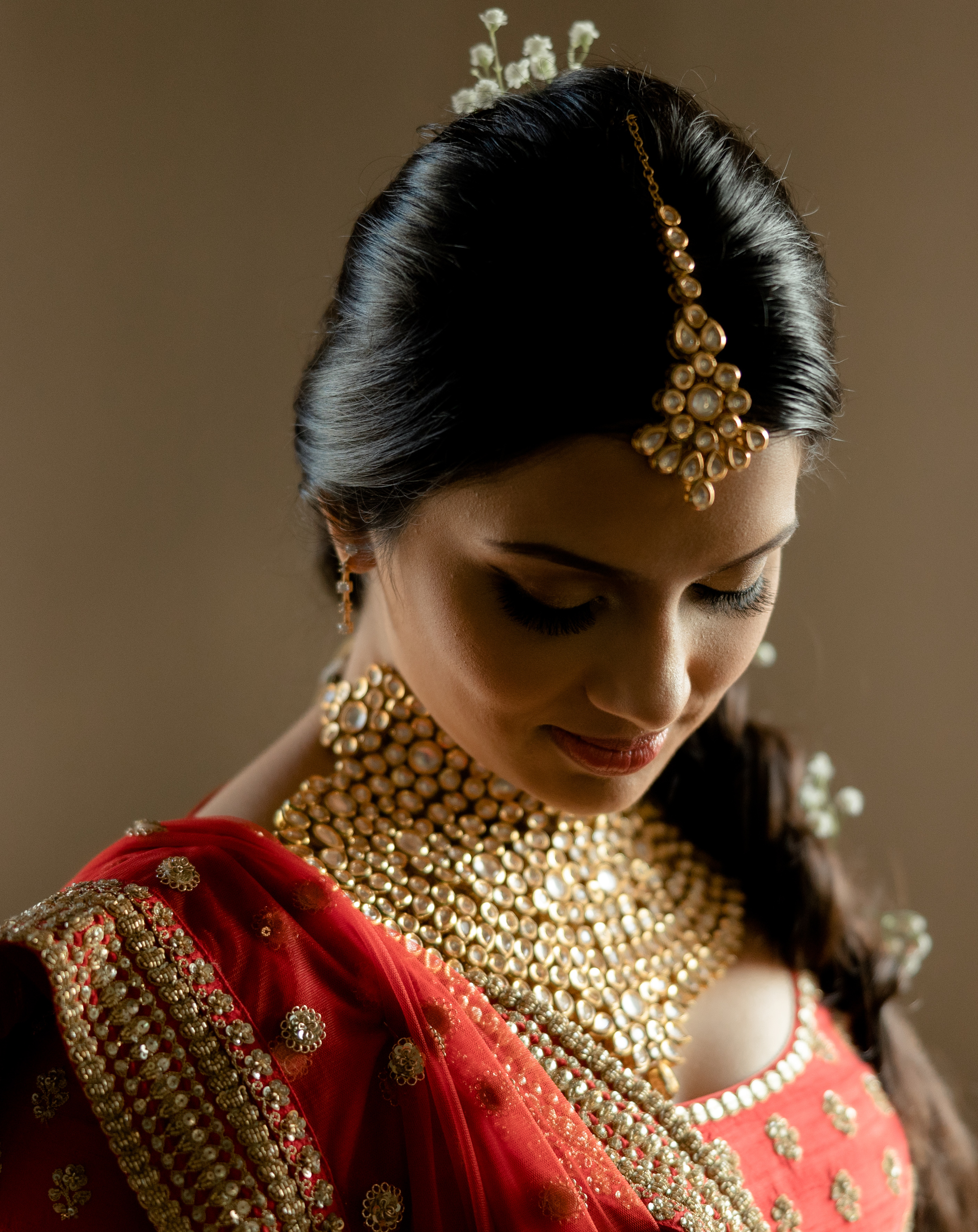 The bride wears traditional gold Hindu jewelry and attire for her wedding ceremony. 