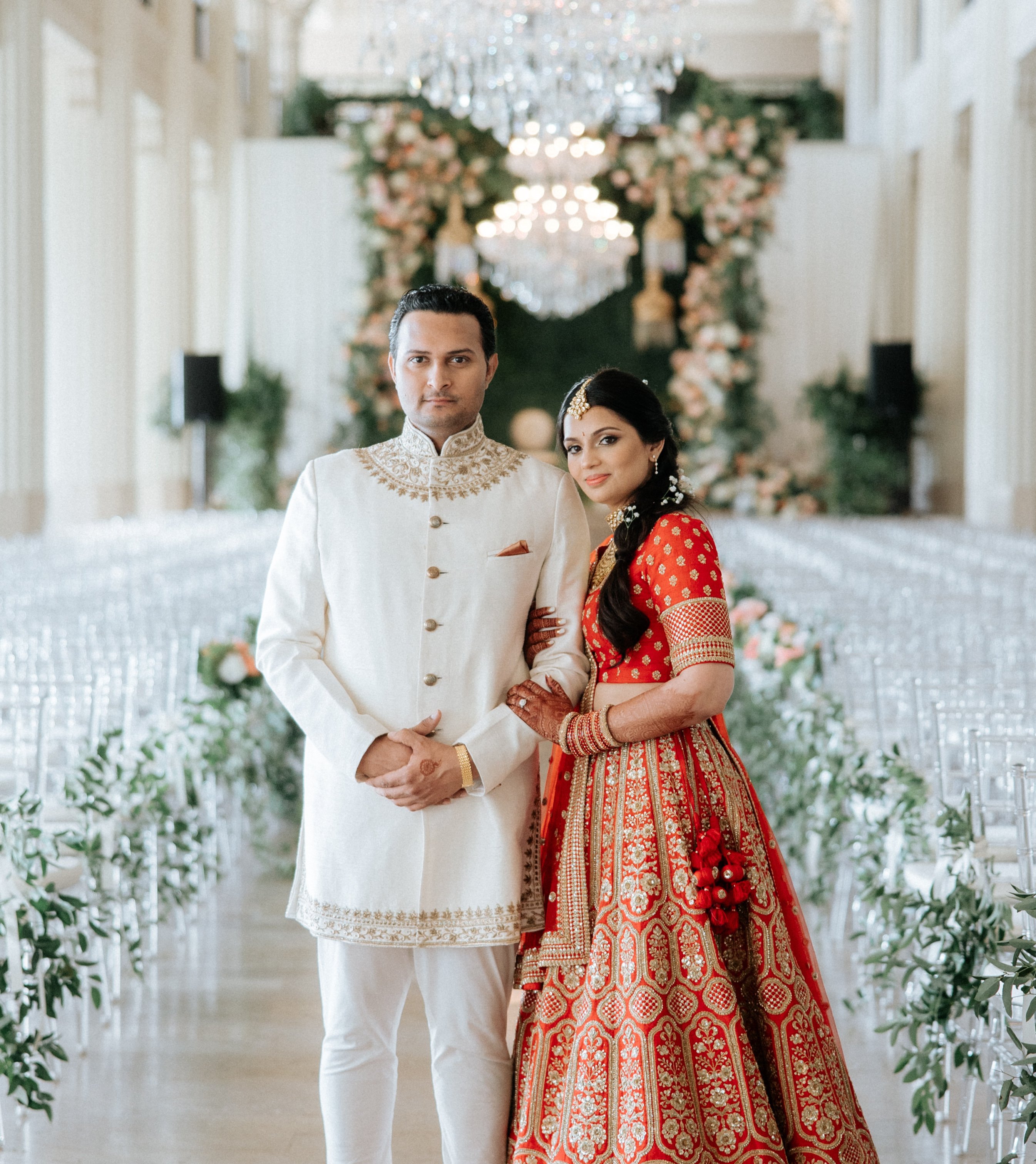 The bride and groom pose for the camera in the ballroom of their Hindu wedding ceremony.
