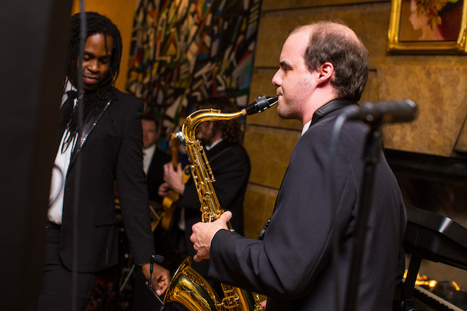 A man from the live music and entertainment band, The Moment, plays the saxophone. 