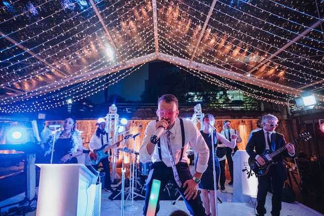 Danny Ray and The Atlantic Street Band perform on a stage at a tent wedding reception in downtown Houston. 