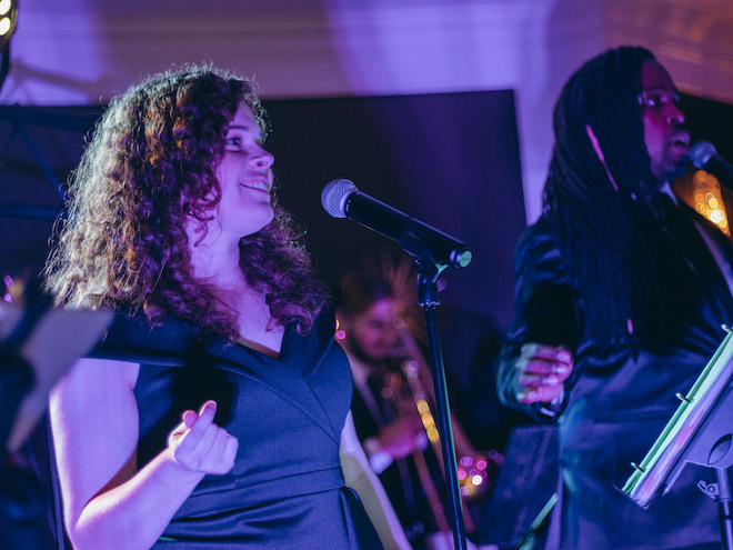 A man and a woman from the live music and entertainment band, The Moment, sing at a wedding reception. 