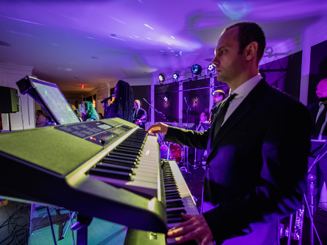 A man from the live music and entertainment band, The Moment, plays the piano at a wedding reception.