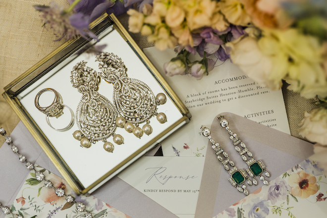 Diamond chandelier earrings, emerald earrings and diamond bracelet from Privosa Fine Jewelry sit on an invitation suite by Wild Wolf Creative at a wedding editorial at The Hundred Oaks. 