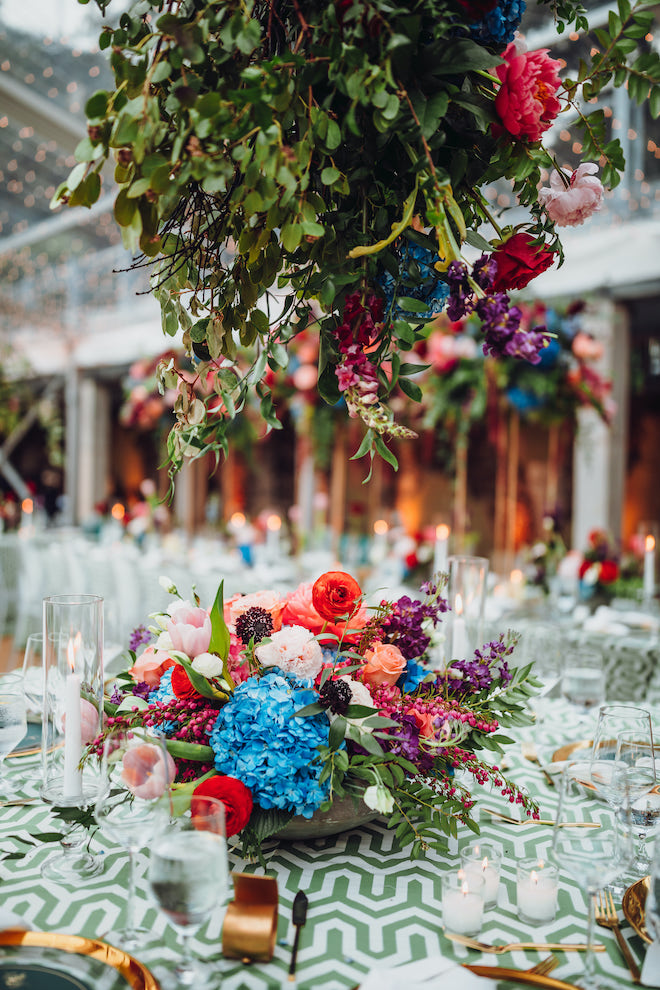 A lush bouquet of blue, peach, red and pink flowers are the centerpieces for the table at the whimsical tent wedding in Downtown Houston. 