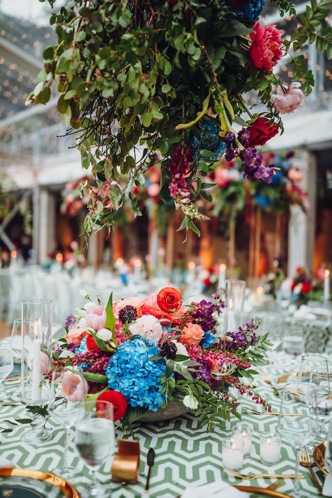 A lush bouquet of blue, peach, red and pink flowers are the centerpieces for the table at the whimsical tent wedding in Downtown Houston. 