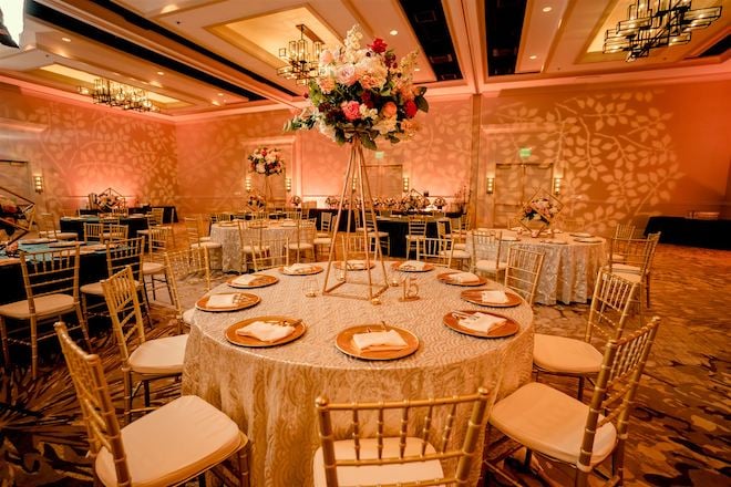Velvet cream tablecloths and gold chargers placed on various tables at the reception.