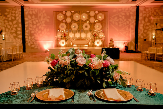 Velvet green tablecloth with gold chargers and a stunning floral centerpiece at the reception.
