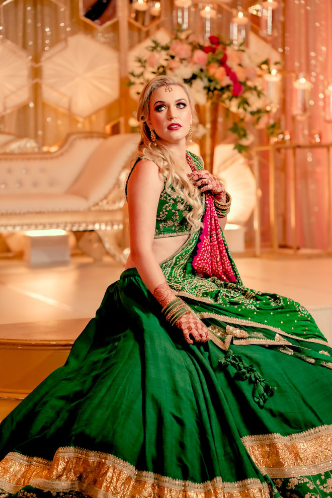 The bride looking to the side in her deep green Lehenga for the reception.