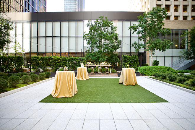 The outdoor area behind the C. Baldwin hotel with three tables placed with tuscan yellow tablecloths.