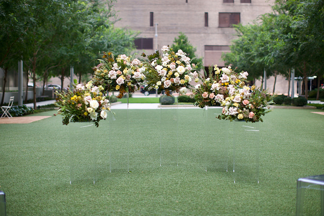 Ceremony set up of Pompom Florists bouquets placed on lucite stands for a modern minimalist look.