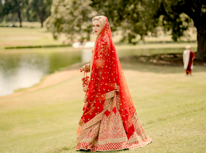 The Bride posing for a picture in a bright red Lehenga 