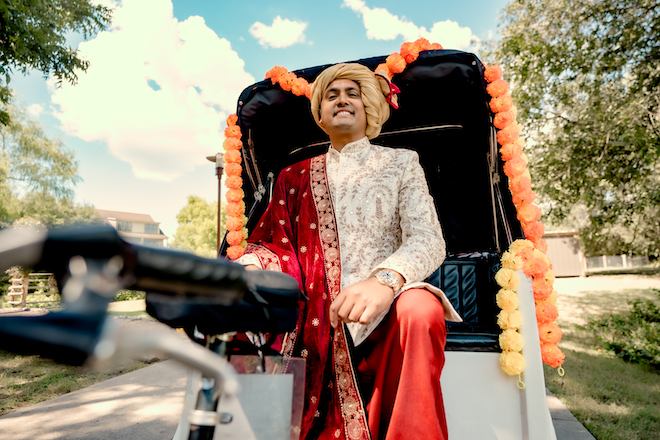 The groom riding on a bike for the Baraat before the Indian fusion wedding ceremony.
