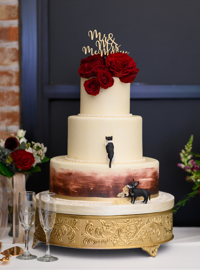 A 3-tier wedding cake decorated with red roses and replicas of the bride and groom's cat and dog at a wedding reception at Sam Houston Hotel. 