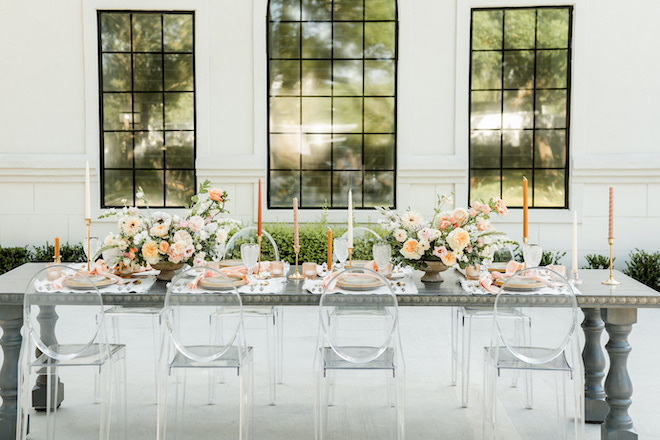 Peach, pink and white flowers and plates set the table outside at the wedding venue. 