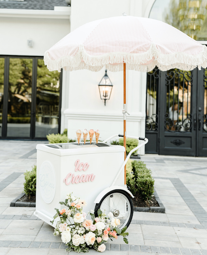 A white and pink vintage ice cream cart sit outside the wedding venue, The Peach Orchard. 