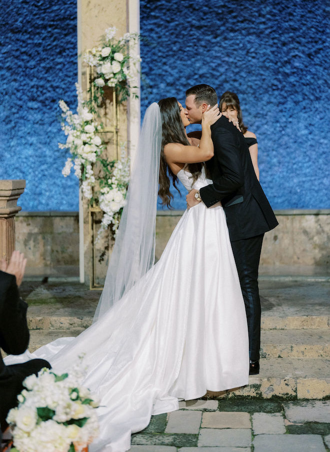 A newly married bride and groom kiss in front of a waterwall. 