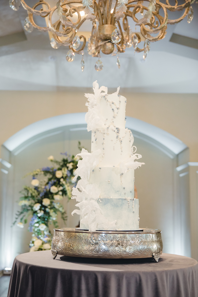 A Four Tier White Wedding Cake With White Embellishments and silver accents at a vow renewal at pine forest country club in houston,texas. 