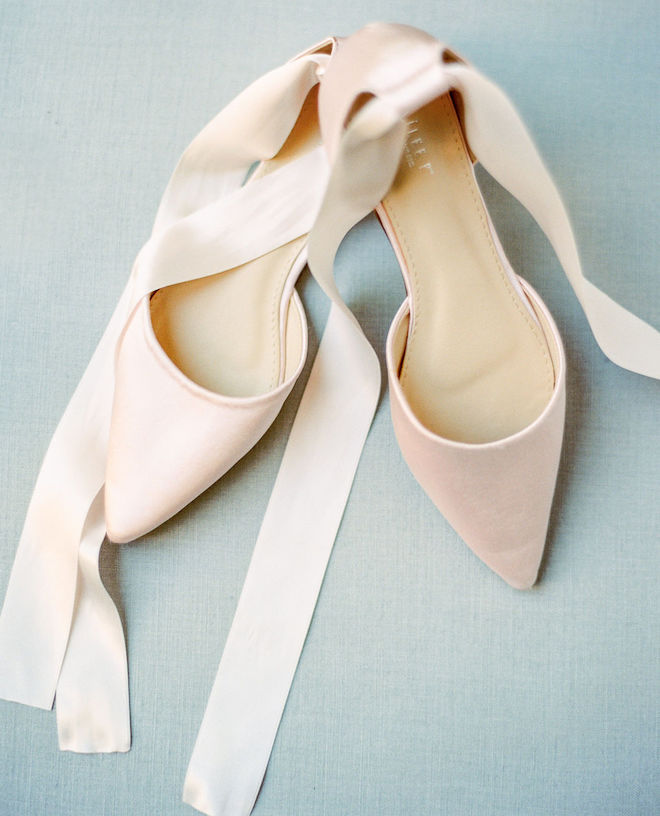 A pair of blush bridal flats with satin ribbons attached 