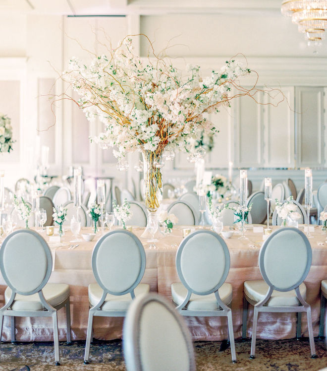 Reception table with light blue chairs and cherry blossom centerpieces.