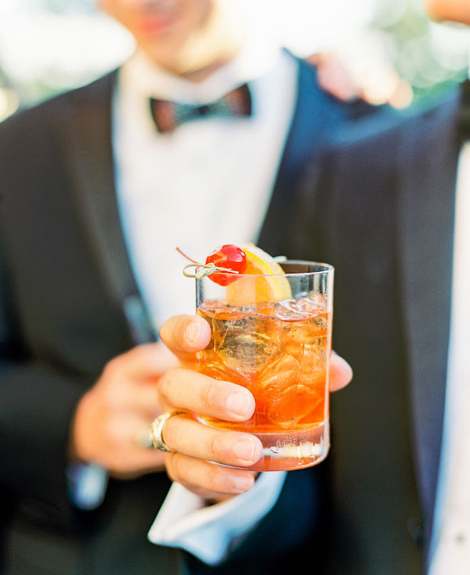 The groom holding a cocktail. 