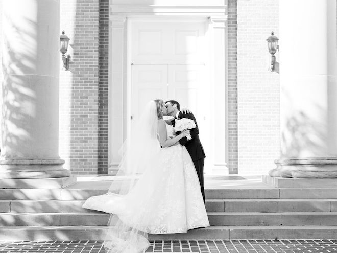 The bride and groom kissing in front of the church they got married in.