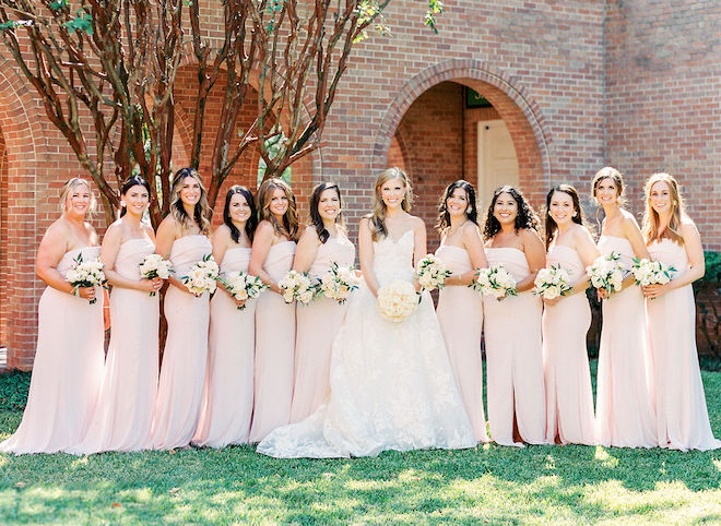 The bride posing with her bridesmaids in blush dresses with their bouquets. 