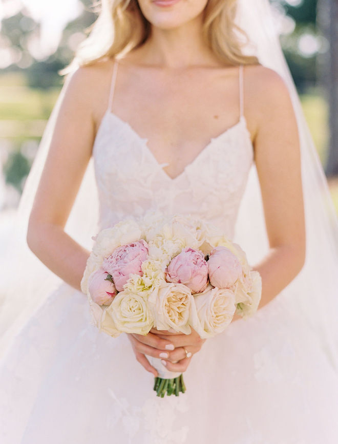 The bride holding her blush and ivory bouquet in her Monique Lhuillier dress.