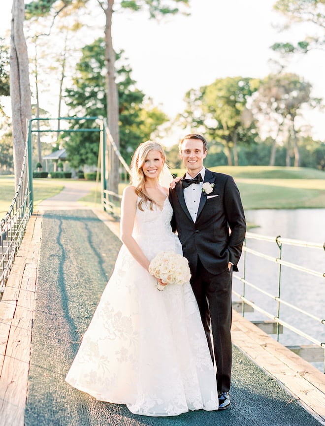 The bride and groom smiling on a bridge at their blush and ivory autumn wedding.