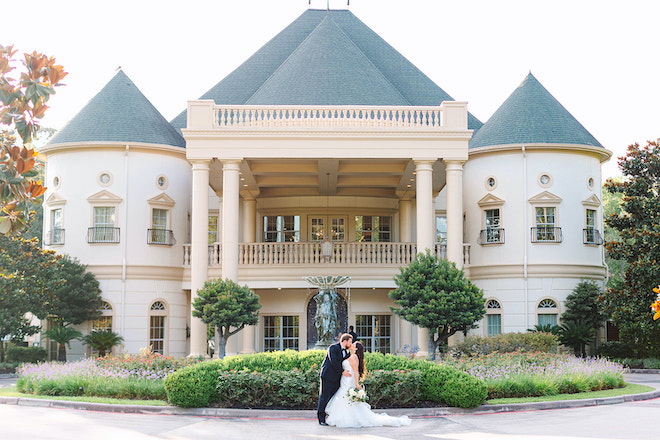 The bride and groom kiss in front of the venue.