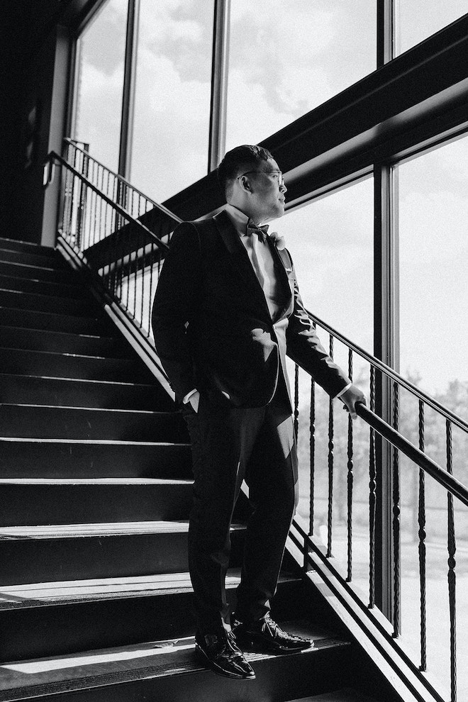 Groom standing on stairs of wedding venue, The Astorian, on his wedding day. 