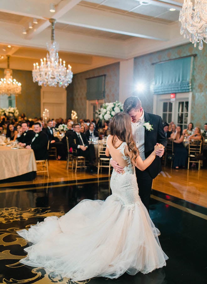 Bride and groom dance on a black dance floor inside a ballroom at their black tie wedding reception in Houston, Texas.