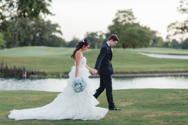 Bride and groom walk hand in hand on the golf course at pine forest country club. 