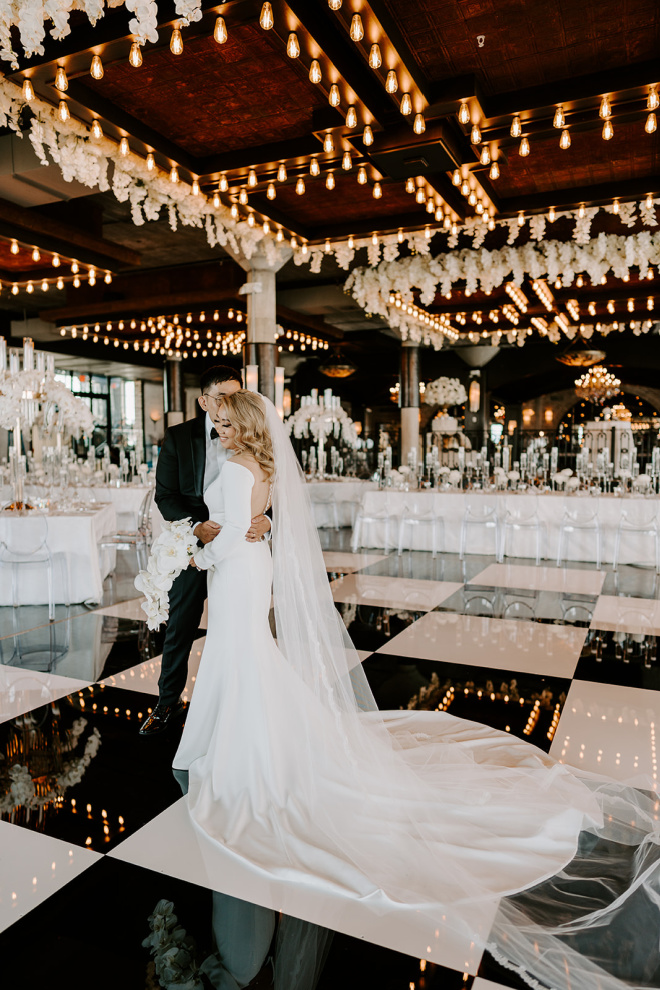 The groom kisses the bride on the cheek as they stand on the dancefloor at their wedding venue, The Astorian.