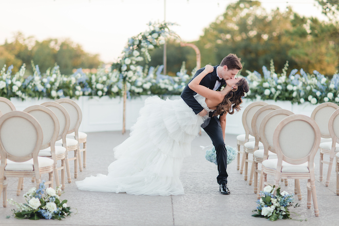 Bride and groom kissing at the end of an aisle at their outdoor vow renewal.