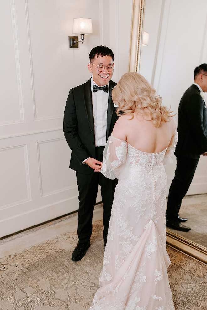Bride revealing her designer wedding reception gown to the groom inside the Soho Suite at wedding venue, The Astorian. 