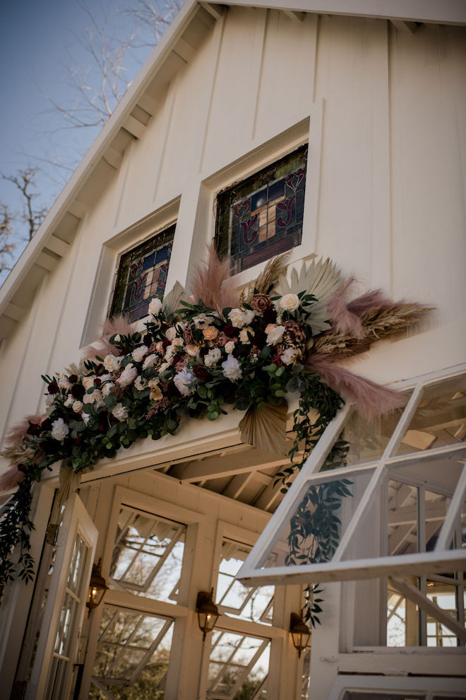 Burgundy and mauve florals draped across the charming white chapel