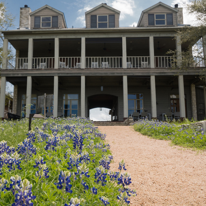 Exterior of the Sage Hill Inn & Spa, with bluebonnets in the grass.