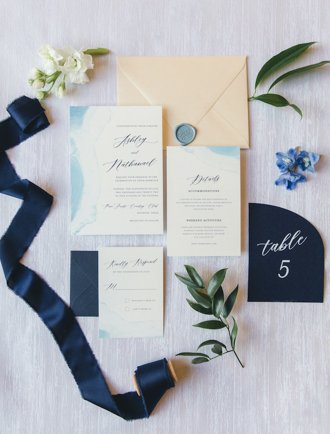 Ivory and light blue invitation suite by Wild Wolf Creative with cursive writing that reads, "Ashley and Nathaniel" at a vow renewal at Pine Forest Country Club. 