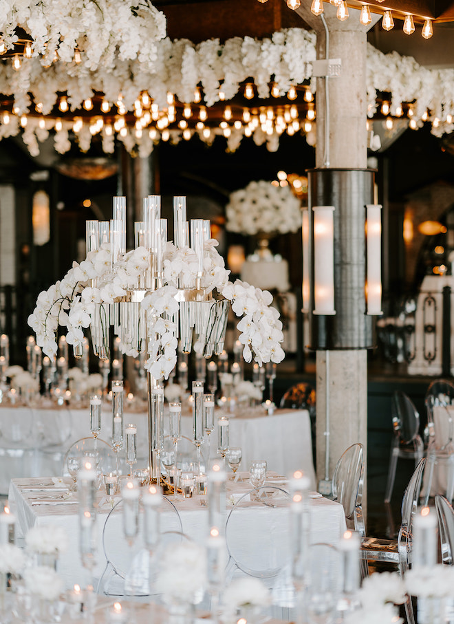 The ballroom of The Astorian decorated for a wedding reception with lit votives, lit candle centerpieces and stems of calla lilies.