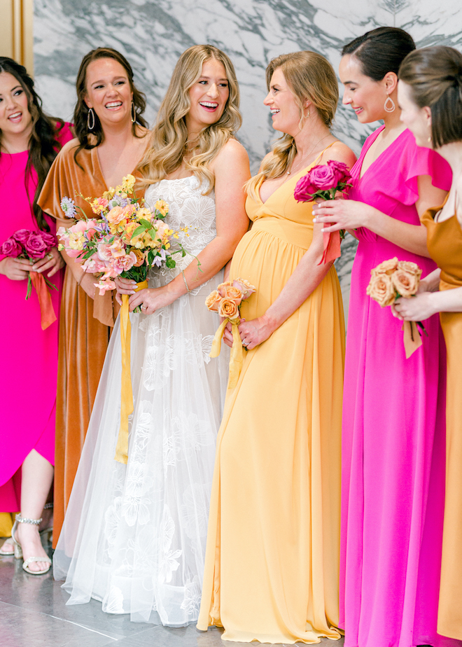 The bride and her bridesmaids wearing colorful shades of pink, orange and yellow.